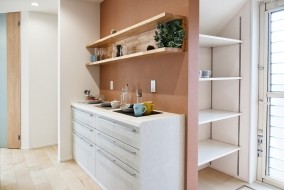 （C棟）温かみのあるの壁が主役のキッチン背面。大容量のカップボードに加え、奥には可動棚付きのパントリーを完備