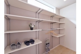 （C棟）大容量の可動棚を備えた、機能的なシューズクロークです。ハンガーパイプ付きで、コートや傘もスマートに収納可能。上部の窓から差し込む光が、明るく清潔感のある玄関周りを演出します。